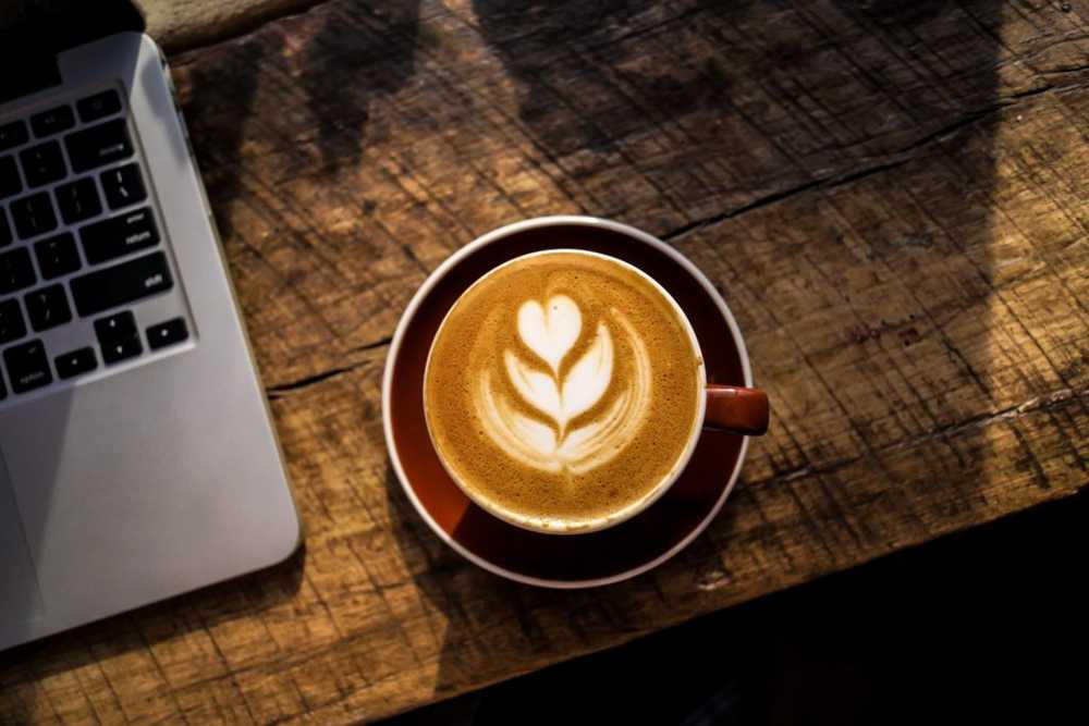 laptop and cup of cappuccino on wooden table