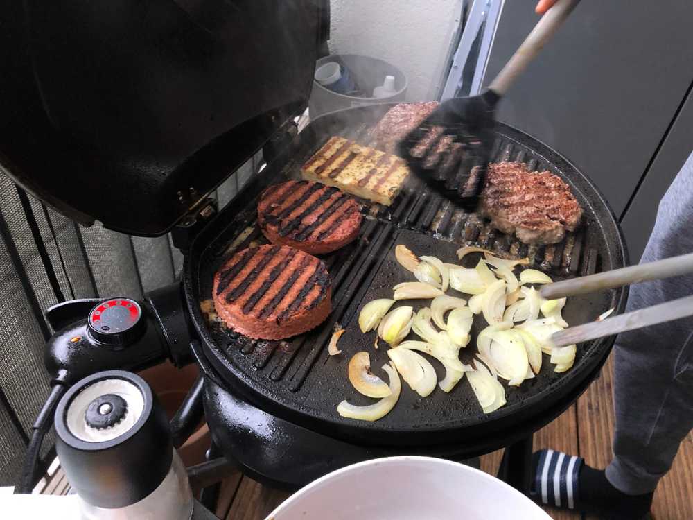 vegan patty grill next to actual meat steaks