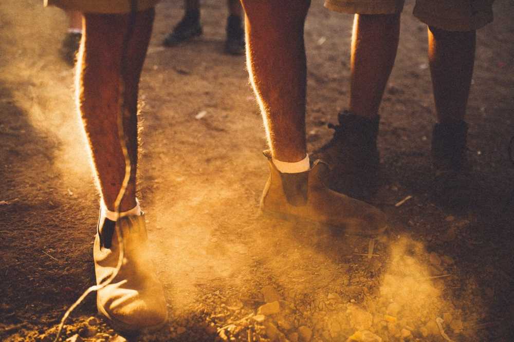 two people in boots standing with sand suspended around their feet