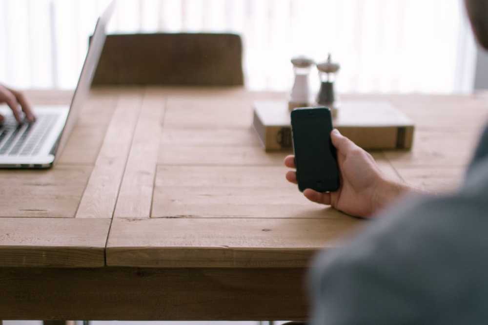 a person using an iphone next to a laptop